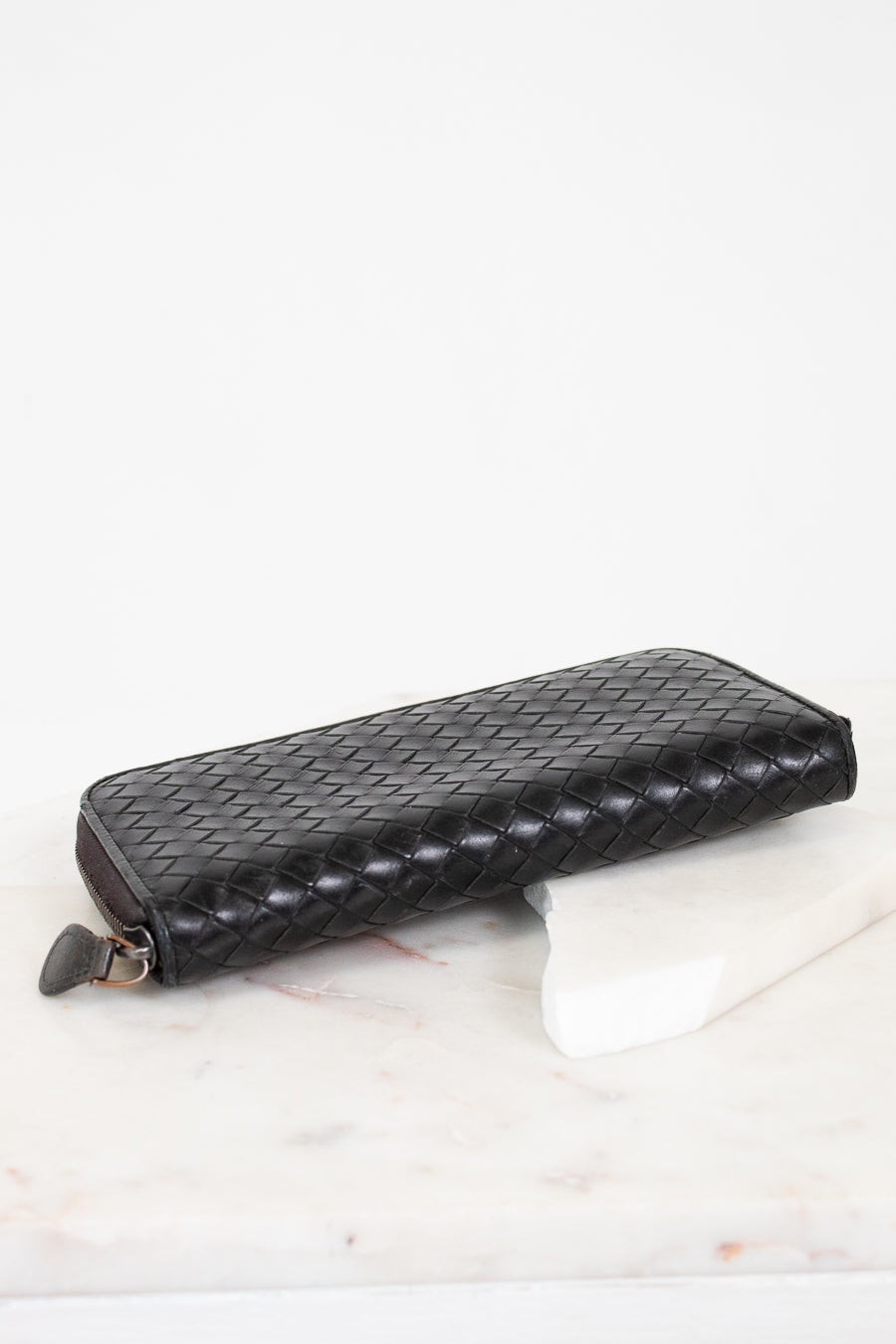 Black woven wallet on a white surface