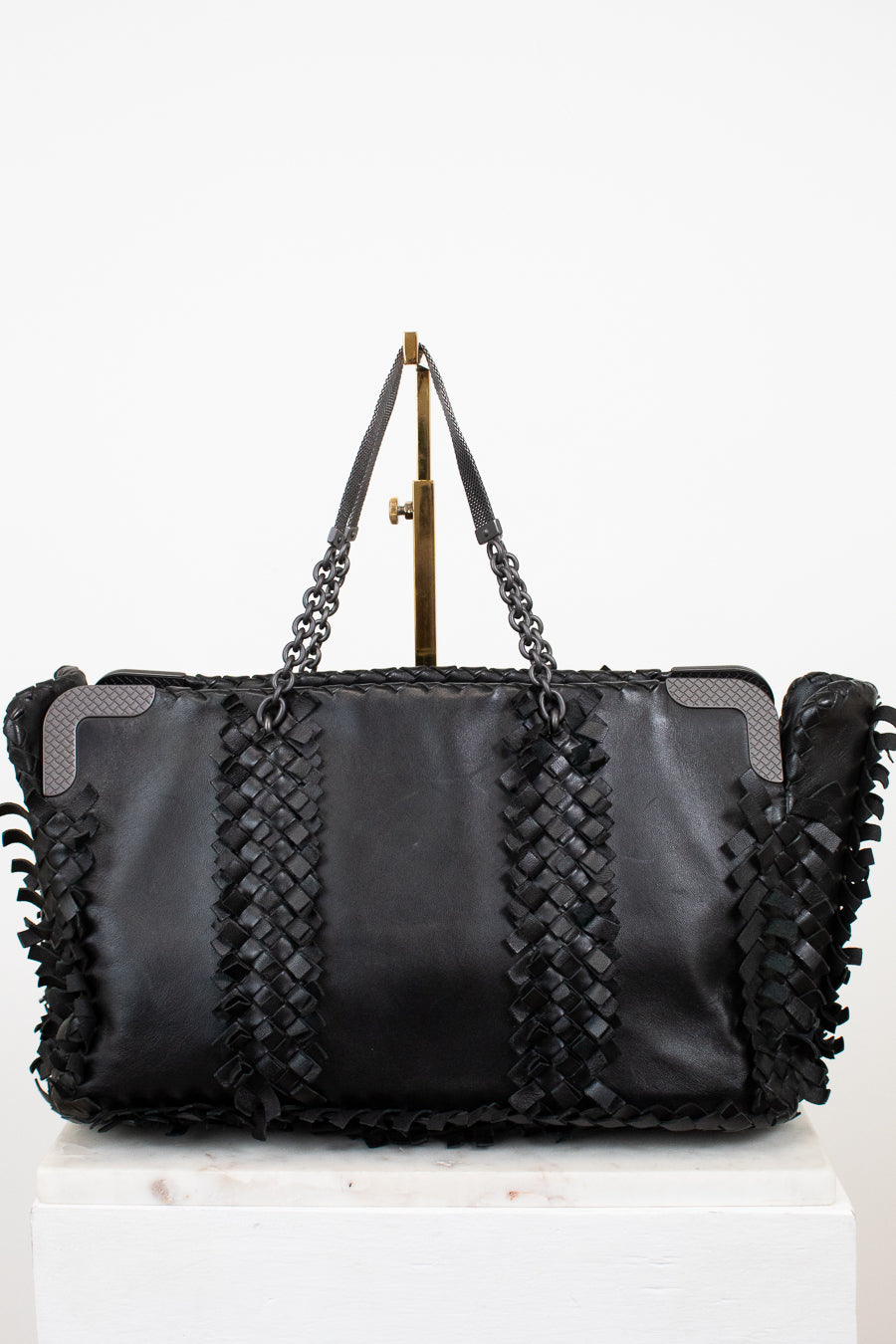 Black leather handbag with braided design and chain strap on a white background