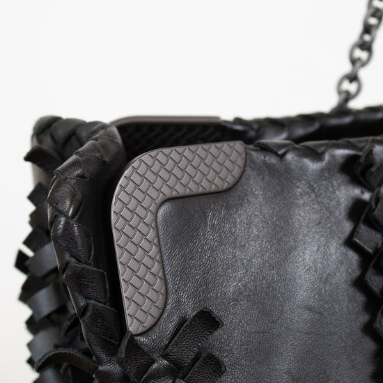 Close-up of a black woven handbag with a textured flap.