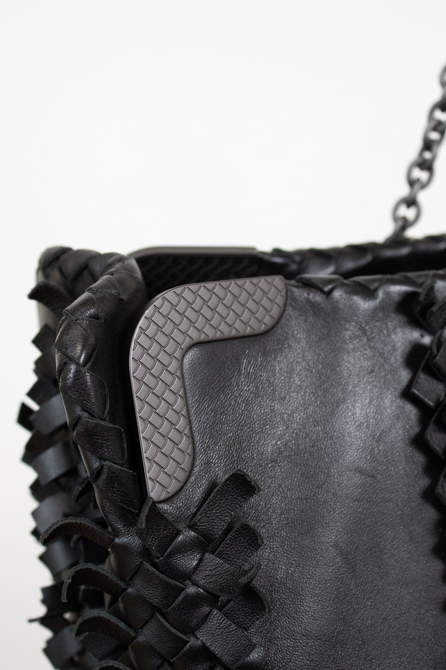 Close-up of a black woven handbag with a textured flap.