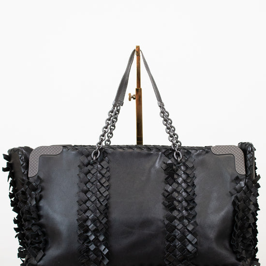 Black woven handbag with chain detail on a white background