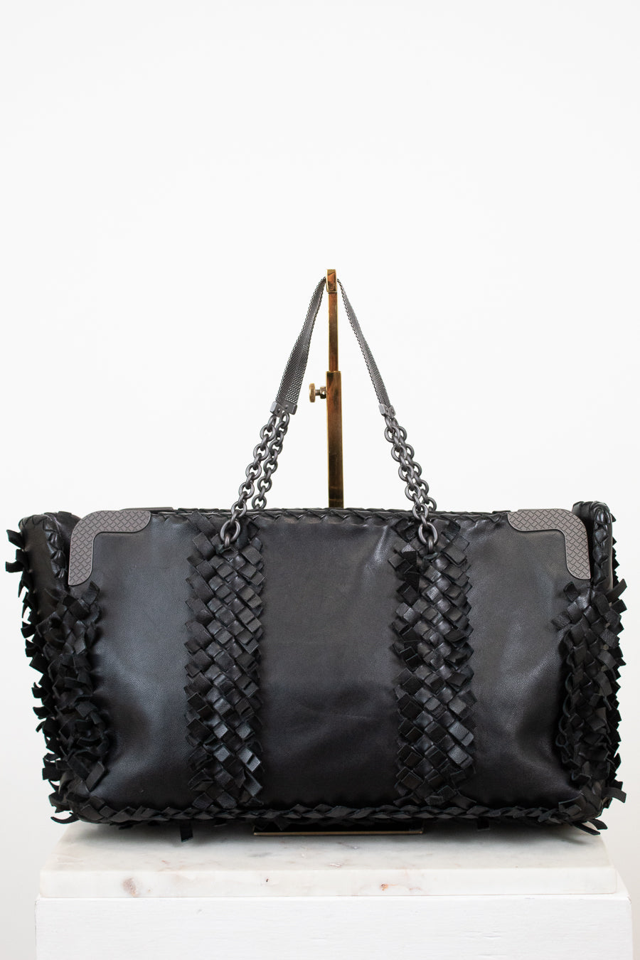 Black woven handbag with chain detail on a white background