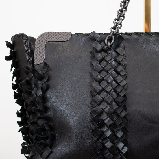 Black handbag with woven detail and chain strap on a white background
