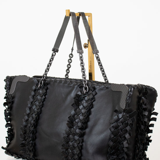 Black handbag with woven straps on a white background