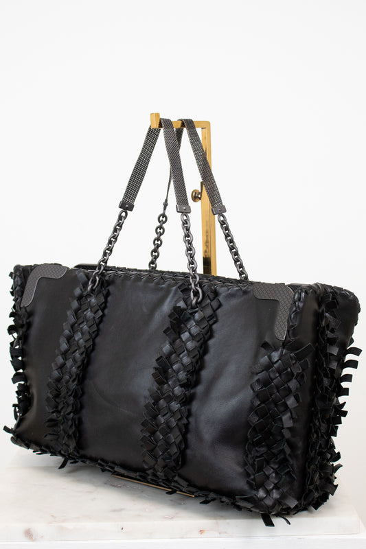 Black handbag with woven straps on a white background