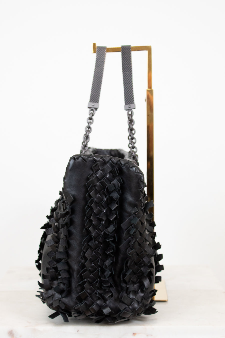 Black textured handbag with chain details on a white background