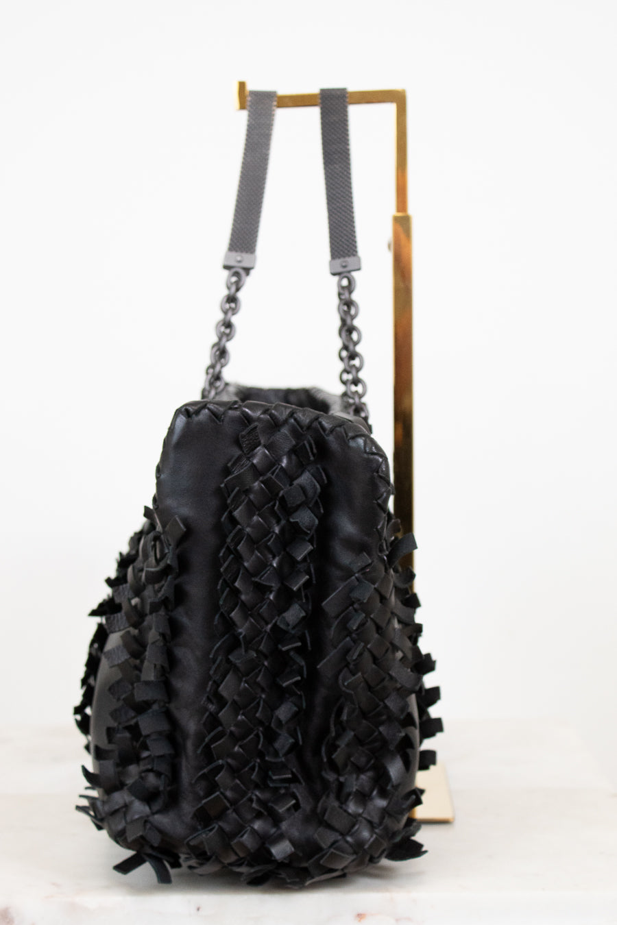 Black textured handbag with chain details on a white background
