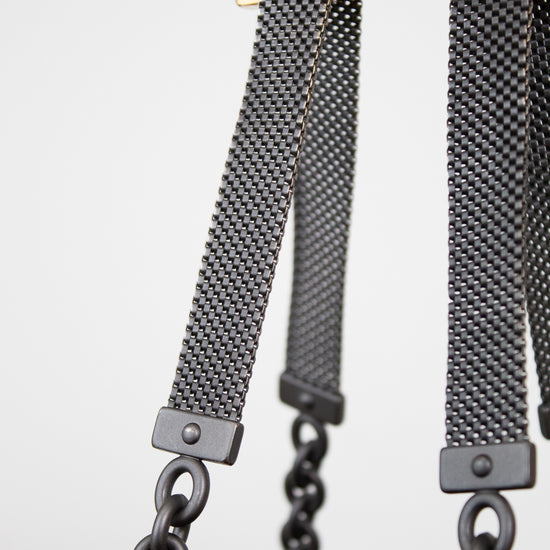 Close-up of a watch strap with black chain on a light gray background