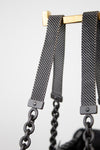 Close-up of a watch strap with black chain on a light gray background