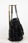 Black woven handbag with chain detail on a white background