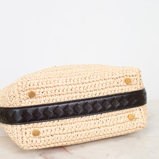 Woven beige handbag with a black strap on a marble surface