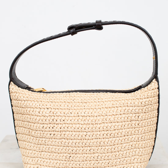 Beige woven handbag with black handle on a light gray background