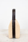 Beige woven handbag with a black handle on a white background