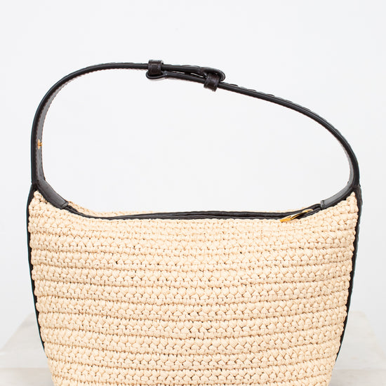 Woven handbag with black leather trim on a white background