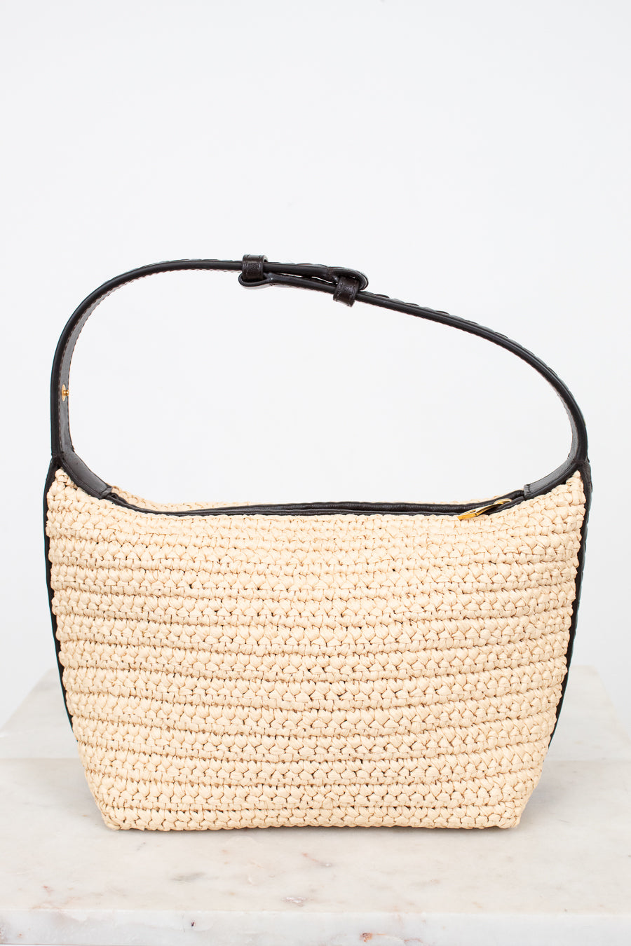 Woven handbag with black leather trim on a white background