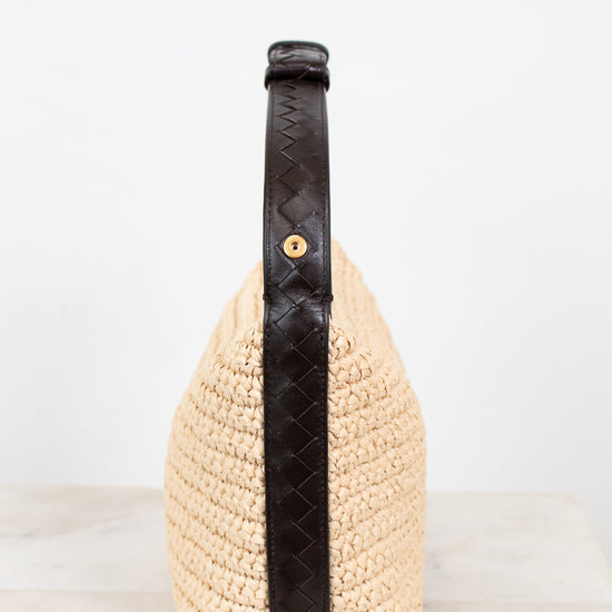 Woven handbag with a black strap on a light background