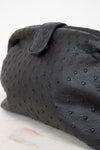 Black textured clutch bag on a light background