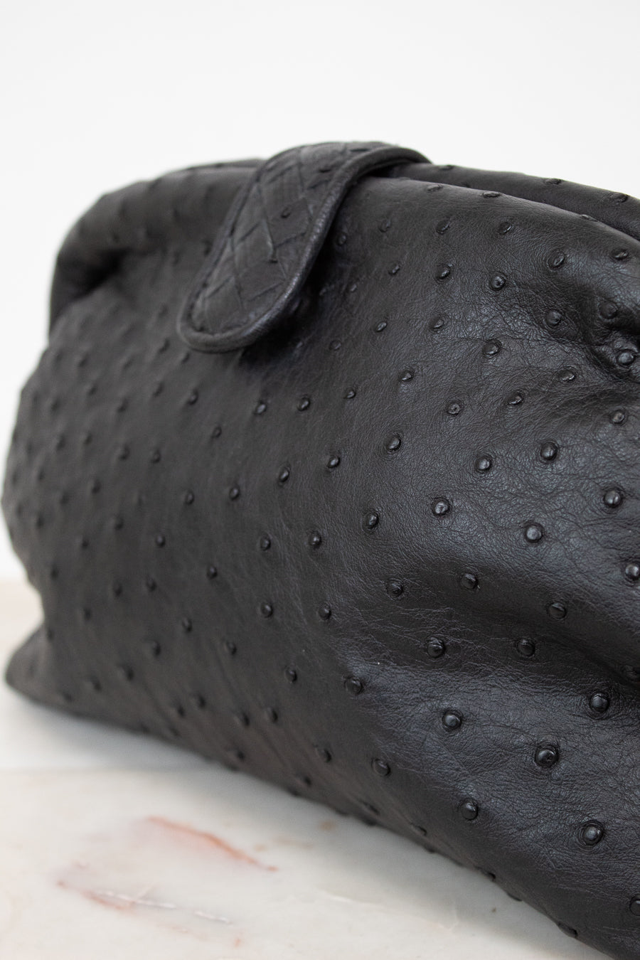Black textured clutch bag on a light background