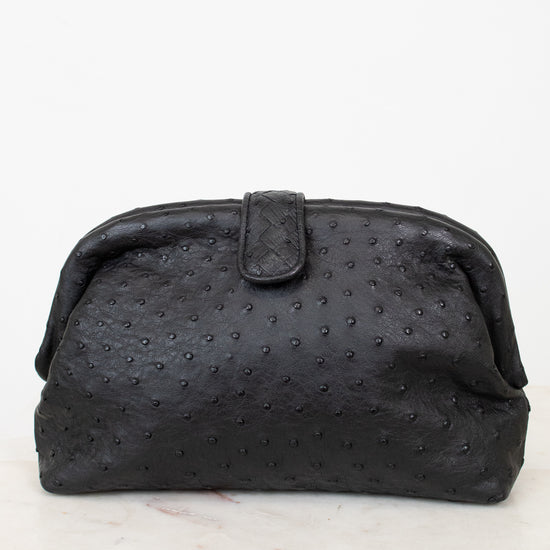 Black textured clutch bag on a white marble surface