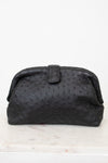Black textured clutch bag on a white marble surface