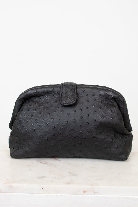 Black textured clutch bag on a white marble surface