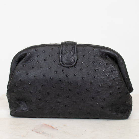 Black textured clutch bag on a white marble surface
