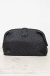 Black textured clutch bag on a white marble surface