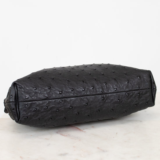Black ostrich-patterned clutch bag on a light marble surface