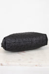 Black ostrich-patterned clutch bag on a light marble surface