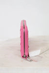 Pink wallet side profile with a zipper on a light marble surface