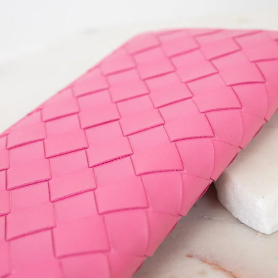 Pink woven wallet on a marble surface