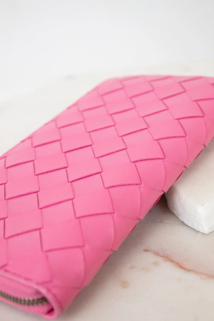 Pink woven wallet on a marble surface