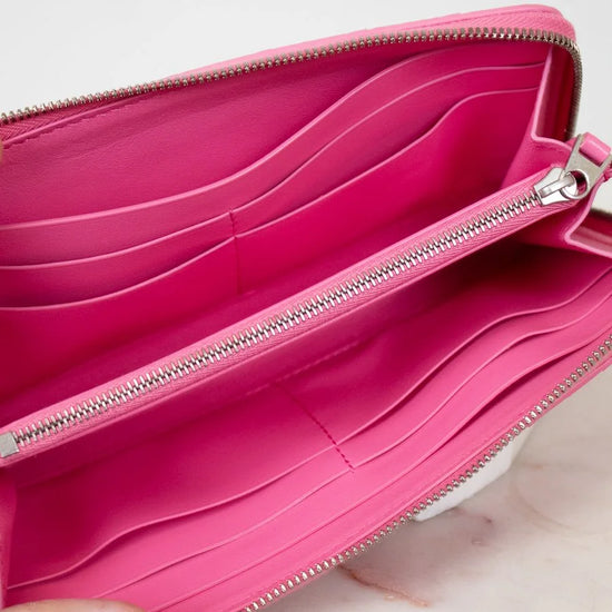 Pink wallet with a hand holding it open on a light background