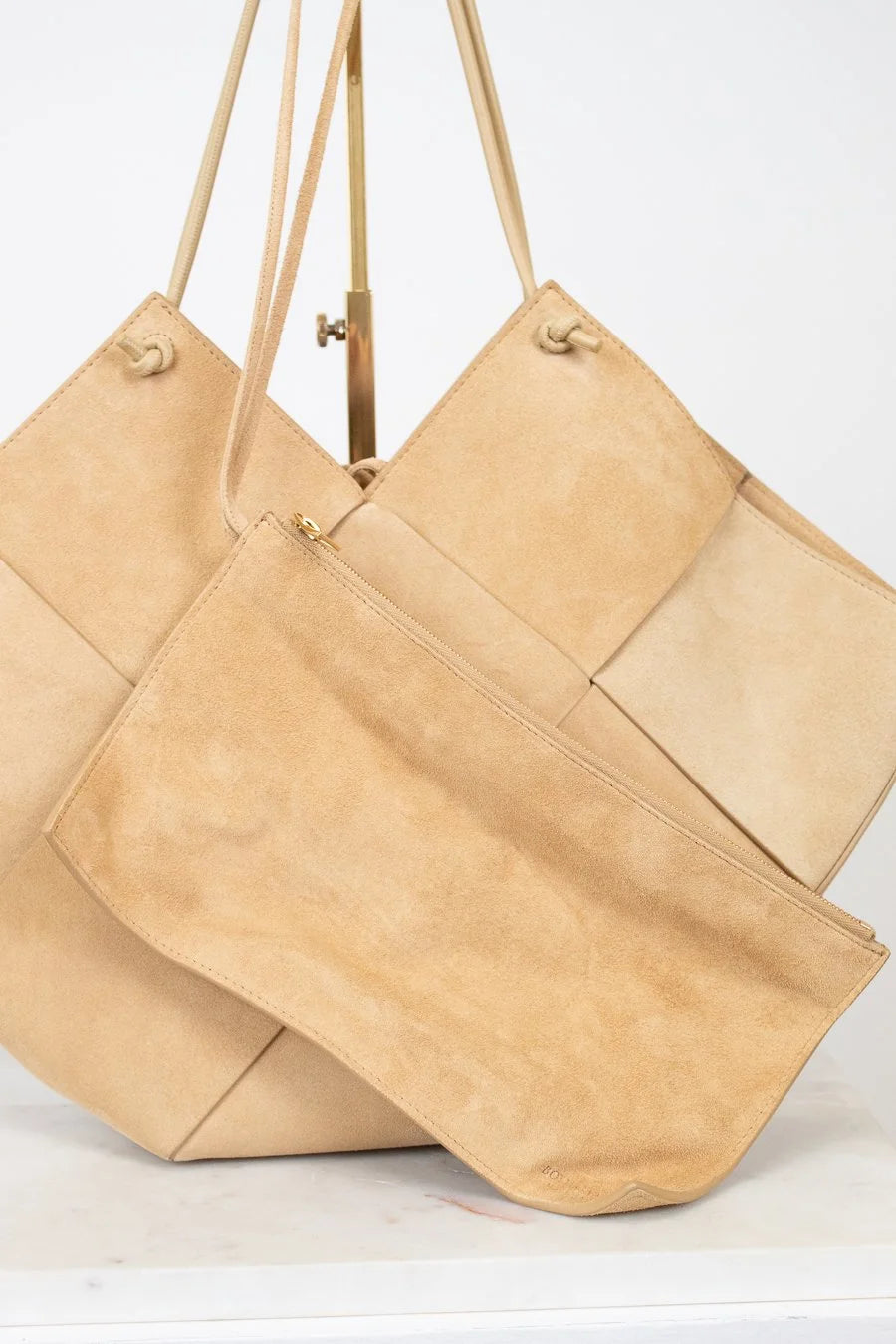 Two beige handbags with leather straps on a white background