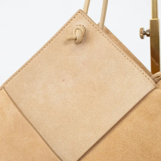 Beige handbag with geometric pattern on a light gray background