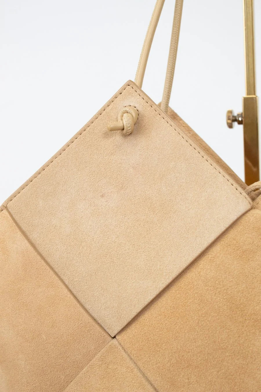 Beige handbag with geometric pattern on a light gray background