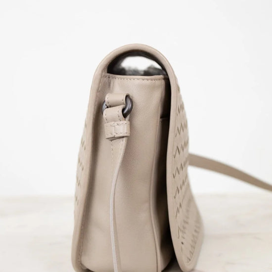 Beige leather bag with a metallic clasp on a white background