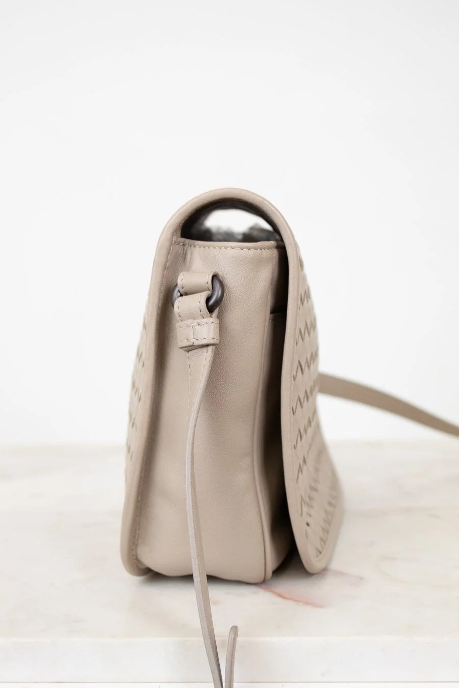 Beige leather bag with a metallic clasp on a white background