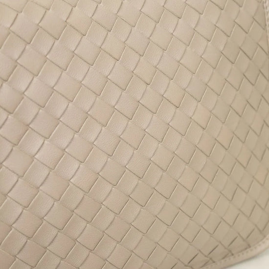 Beige woven clutch bag on a light marble background