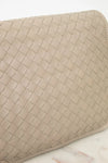 Beige woven clutch bag on a light marble background