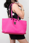 Person holding a pink woven handbag against a plain background