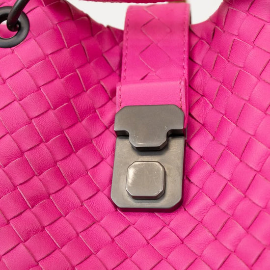 Close-up of a pink woven handbag with a black clasp.