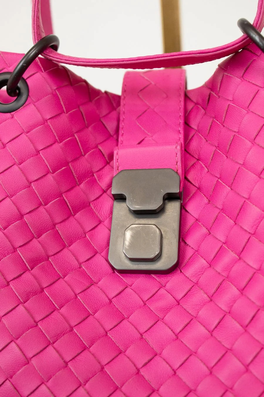 Close-up of a pink woven handbag with a black clasp.