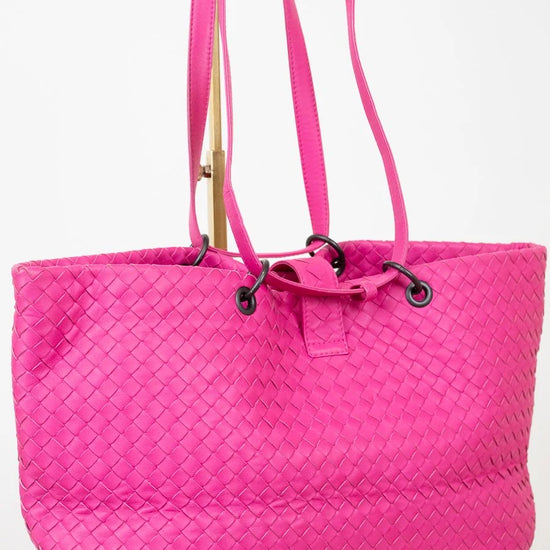 Pink quilted tote bag with a strap on a white background