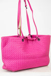 Pink quilted tote bag with a strap on a white background