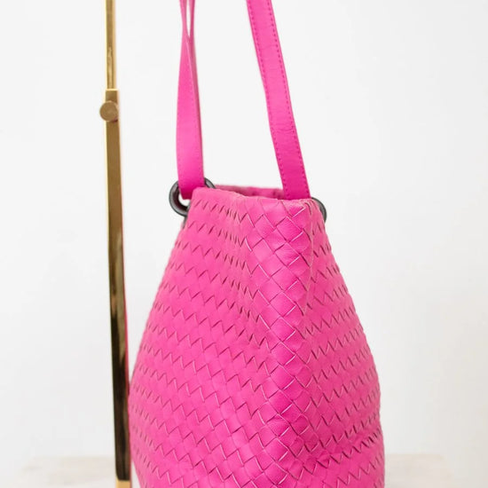 Pink woven handbag with a strap on a white background