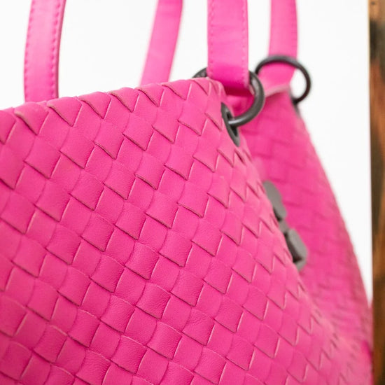 Close-up of a pink woven handbag with a blurred background