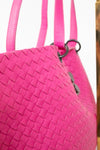 Close-up of a pink woven handbag with a blurred background