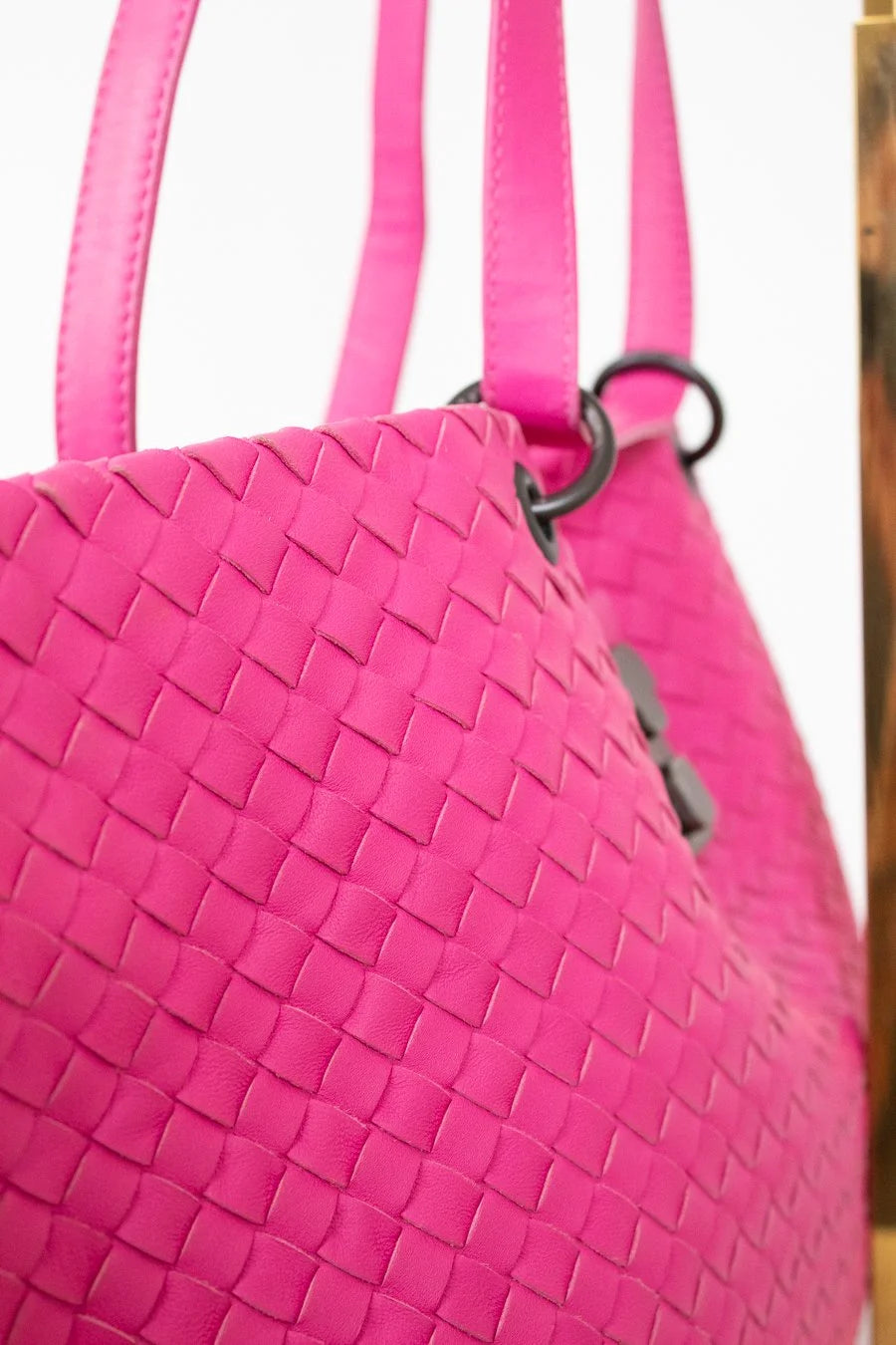 Close-up of a pink woven handbag with a blurred background