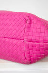 Pink woven handbag on a white background